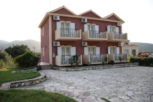 a large red building with balconies and a patio at Ourania Studios in Sami