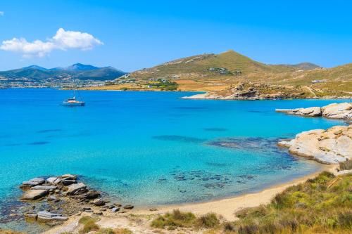 a boat in the water next to a beach at Superb Naxos Apartment Grand Suite In The Heart Of Town Balcony City Views Saint George in Naxos Chora
