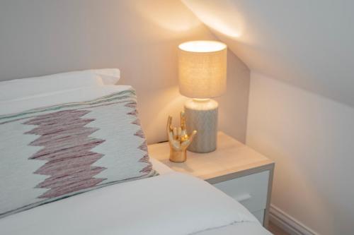 ein Schlafzimmer mit einem Bett und einem Tisch mit einer Lampe in der Unterkunft Stylish home w/ parkng, fst wifi in Cambourne