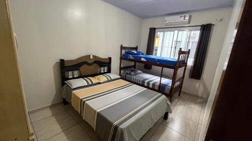 Duas camas num pequeno quarto com uma janela em Casa do aconchego ( terreno compartilhado) em Foz do Iguaçu