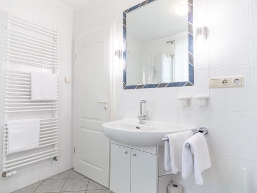 a white bathroom with a sink and a mirror at Strandoase Typ STO-A STRANDOASE Whg. SO5 in Wustrow