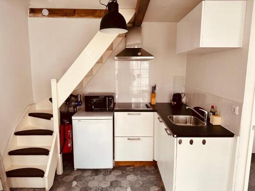 a small kitchen with white cabinets and a staircase at Cosy tiny house in the centre city of Volendam in Volendam