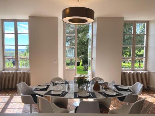 une salle à manger avec une table, des chaises et des fenêtres dans l'établissement Beau château dans le Cantal au coeur du Pays Vert, à Naucelles