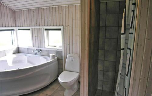 a white bathroom with a tub and a toilet at Holiday Home Strandparken Xi in Otterup