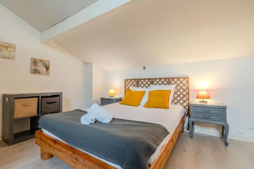 um quarto com uma cama com almofadas amarelas e uma televisão em Atlantic Selection - Le Boudigau avec parking em Capbreton