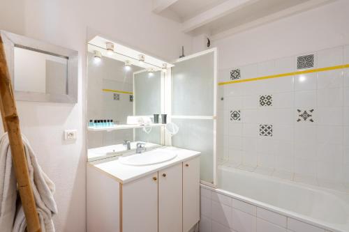 La salle de bains blanche est pourvue d'un lavabo et d'une baignoire. dans l'établissement Atlantic Selection - Le Boudigau avec parking, à Capbreton