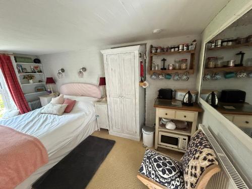 a small bedroom with a bed and a kitchen at Cosy Cottage ground floor bedroom ensuite with private entrance in Chichester