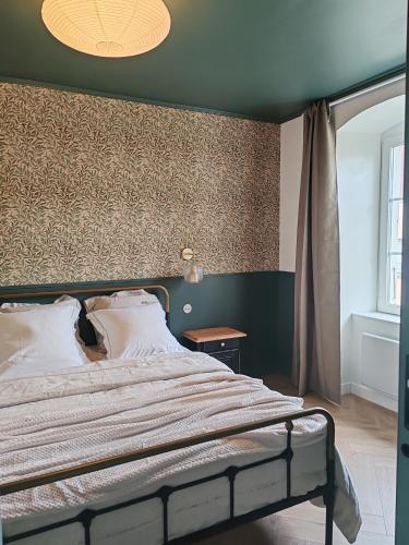 une chambre avec un grand lit et un mur dans l'établissement L'Oiseau vert - calme, ressourçant et proche du centre ville, à Montbéliard