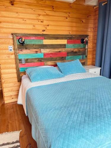 a bedroom with a blue bed with a wooden wall at PEZ HOUSE in Pichilemu