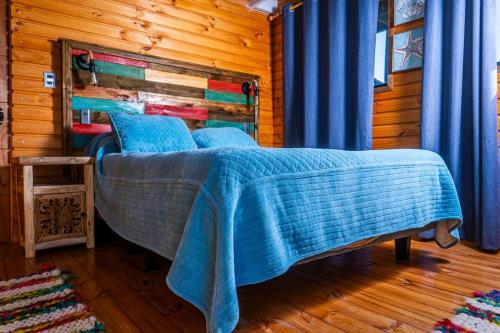 a bedroom with a bed with a blue comforter at PEZ HOUSE in Pichilemu