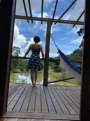 a woman is standing on a wooden bridge at Pousada Caminho dos Ipês in Bocaina de Minas