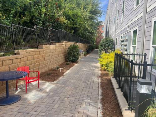 a brick sidewalk with a red chair and a table and a fence at The Vault - Perfect Location! in Oxford