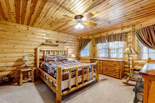 a log cabin bedroom with a bed and a ceiling fan at Getaway on the Green in Arkdale