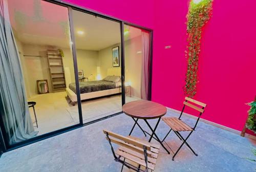 a room with a pink wall and a table and chairs at Casa Isolda in Mexico City