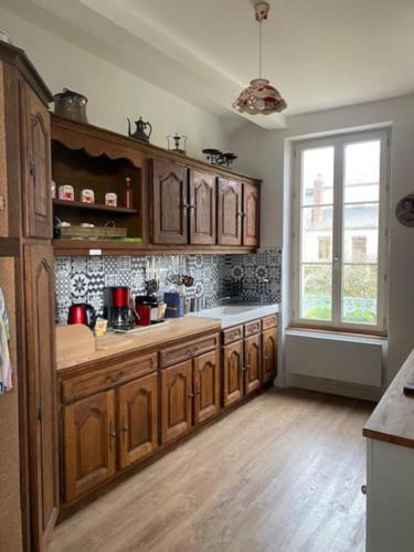 une cuisine avec des armoires en bois et une fenêtre dans l'établissement La Gatinelle, à Treigny