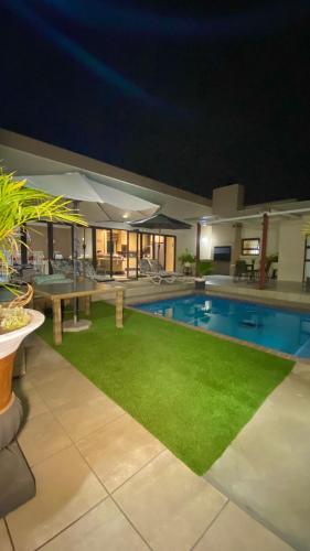 a swimming pool at night with a green lawn at Lerato's in Vanderbijlpark