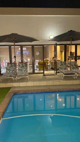 a house with a swimming pool with chairs and umbrellas at Lerato's in Vanderbijlpark