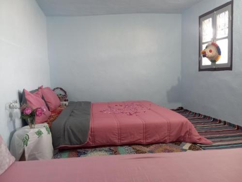a bedroom with a pink bed and a window at Dar Lala Zhour in Aïn Bouchrik