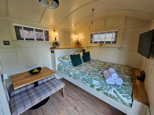 um pequeno quarto com uma cama e uma mesa em Gatwick Hideaway Hut em Charlwood