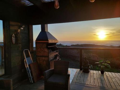 a fireplace on a deck with a sunset in the background at PEZ HOUSE in Pichilemu
