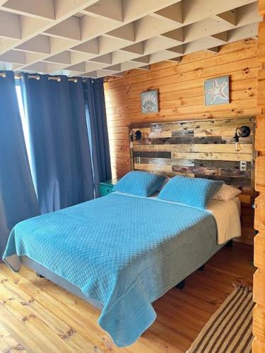 a bedroom with a bed with a wooden wall at PEZ HOUSE in Pichilemu
