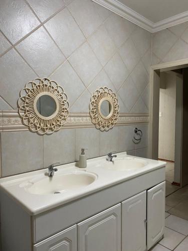 a bathroom with two mirrors and a white sink at Lerato's in Vanderbijlpark