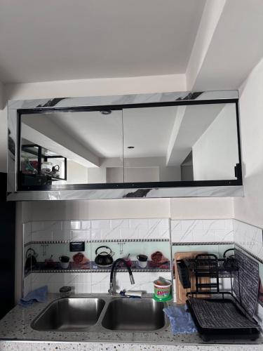 una cocina con fregadero y un espejo encima. en Departamento Amoblado Vista Externa, en Huánuco