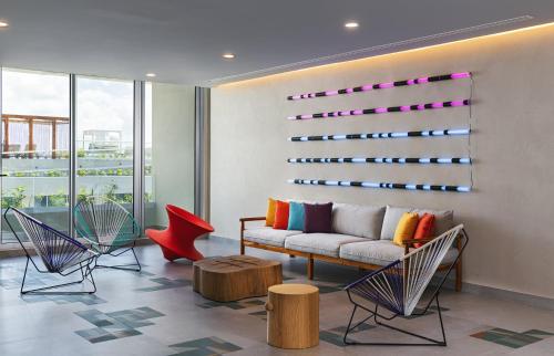 a living room with a couch and chairs at Aloft Playa del Carmen in Playa del Carmen