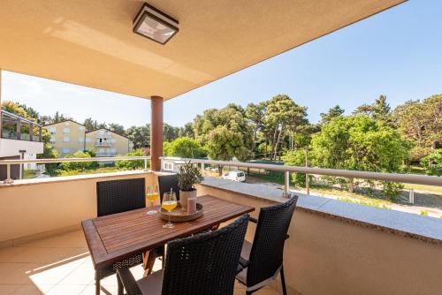 a patio with a wooden table and chairs on a balcony at Apartments L&D in Biograd na Moru