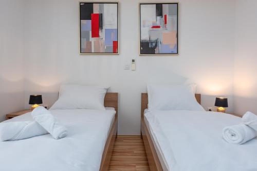 two twin beds in a room with two pictures on the wall at Apartments L&D in Biograd na Moru