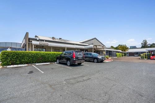 a parking lot with two cars parked in front of a building at Morayfield Tavern in Morayfield