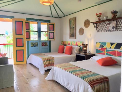 a bedroom with two beds and a room with windows at Mamatina Hotel in Santa Rosa de Cabal