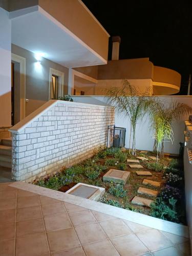 a house with a brick wall and a garden at Casa Mandorle in Ugento
