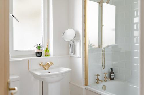 een witte badkamer met een wastafel en een douche bij Charming LDN apt with free parking in Londen