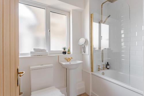 een witte badkamer met een wastafel en een douche bij Charming LDN apt with free parking in Londen