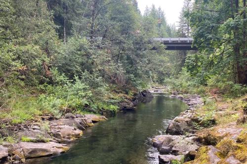 a river with a bridge in the background at River Time Retreat in Carson