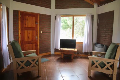 拉戈普艾羅的住宿－Chacra confluenza，客厅配有两把椅子和电视