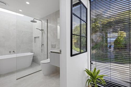 a bathroom with a tub and a toilet and a window at Vista Mare in Wellington