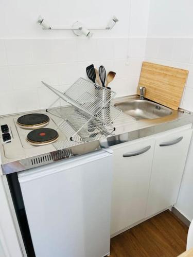 une cuisine blanche avec une cuisinière et un évier dans l'établissement Studio proche Part-Dieu, à Villeurbanne