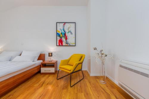 a bedroom with a bed and a yellow chair at Apartments L&D in Biograd na Moru