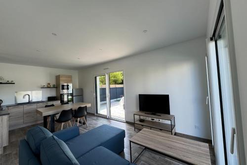 een woonkamer met een blauwe bank en een tv bij Splendid new house in Ouistreham in Ouistreham