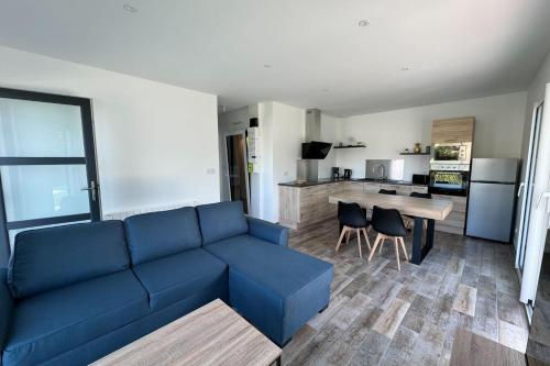 een woonkamer met een blauwe bank en een keuken bij Splendid new house in Ouistreham in Ouistreham
