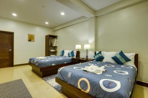 a bedroom with two beds with blue and white sheets at Louis' Apartments in Placencia Village