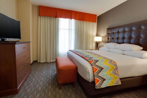 a hotel room with a bed and a flat screen tv at Drury Inn & Suites Charlotte Arrowood in Charlotte