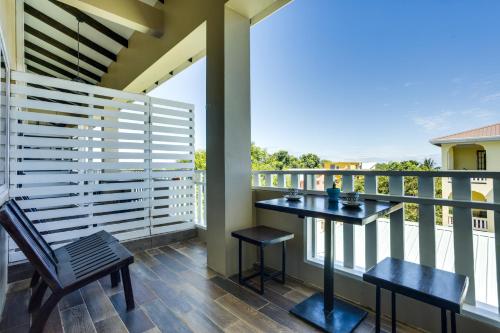 a balcony with a table and two stools at Louis' Apartments in Placencia Village