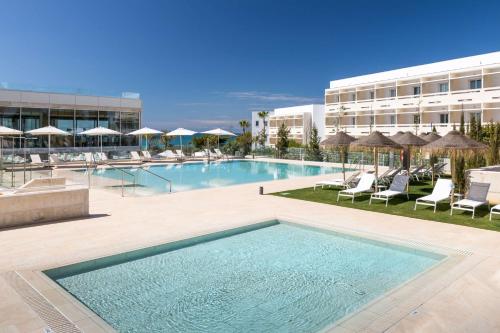 une grande piscine avec des chaises et un bâtiment dans l'établissement Barceló Conil Playa - Adults Recommended, à Conil de la Frontera