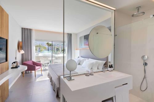 ein Hotelzimmer mit einem Bett und einem Spiegel in der Unterkunft Barceló Conil Playa - Adults Recommended in Conil de la Frontera