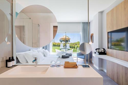 a bathroom with a large mirror and a living room at Barceló Conil Playa - Adults Recommended in Conil de la Frontera