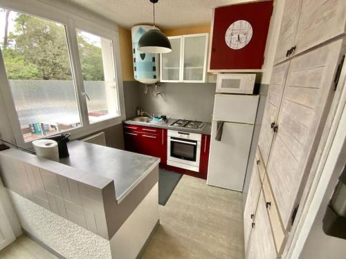 une cuisine avec des armoires rouges et un réfrigérateur blanc dans l'établissement Appartement cosy en bord de mer, à La Tranche-sur-Mer