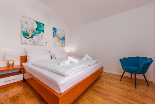 a bedroom with a bed and a blue chair at Apartments L&D in Biograd na Moru